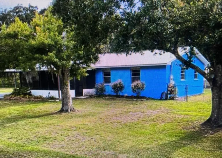Renovated blue CBS country home with a metal roof on a large shaded lot