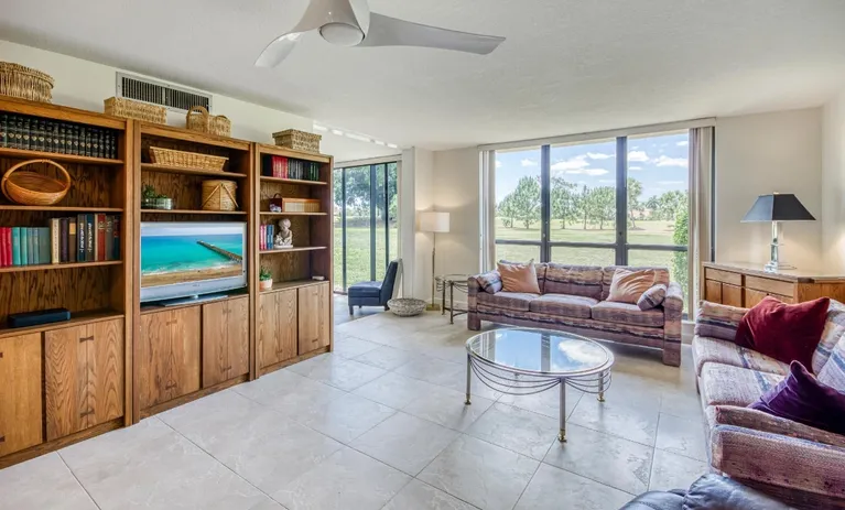 Sunny living room with built-in shelves and a golf course view