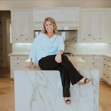 Merideth McNamee, Realtor, seated on a marble kitchen island